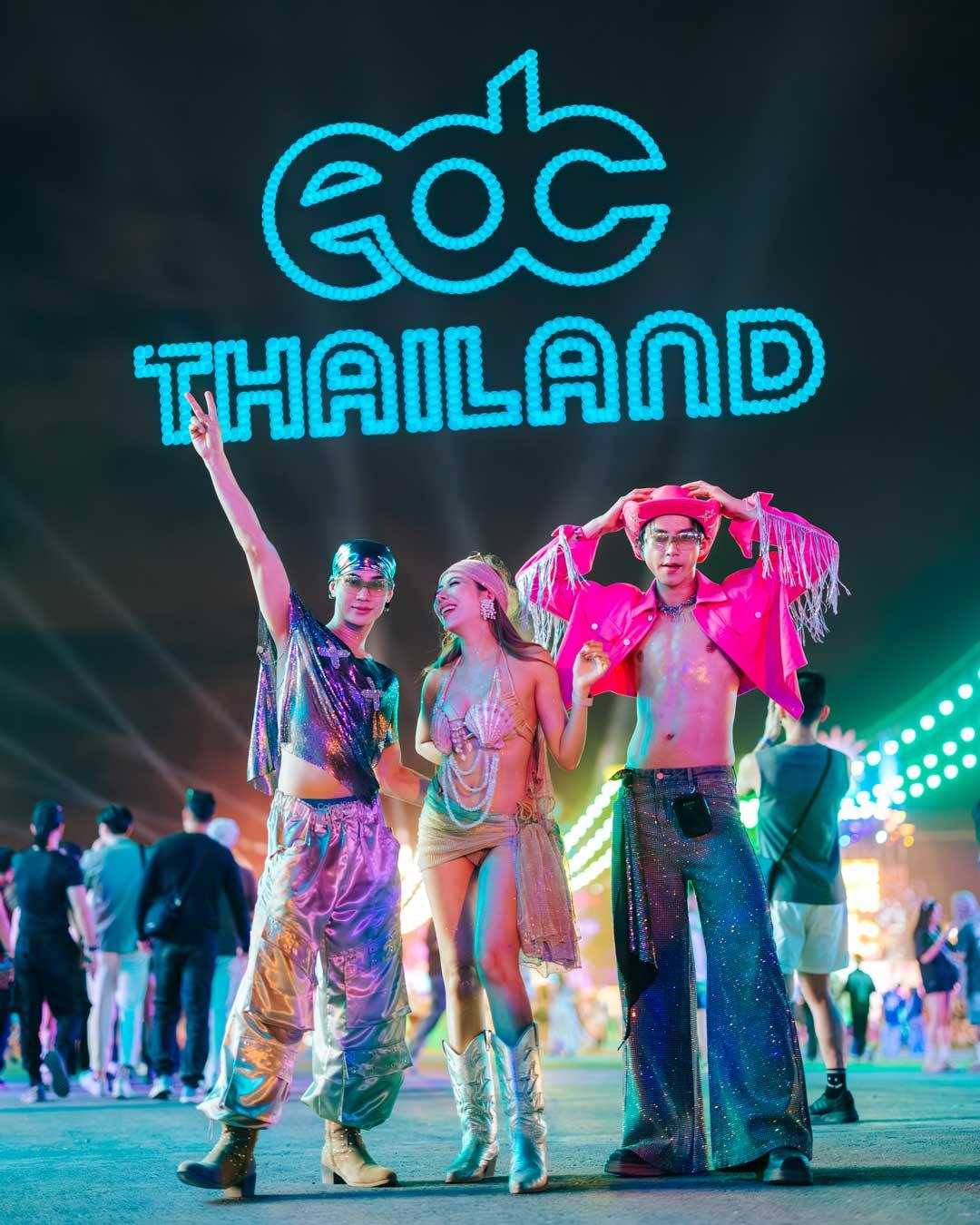 Festival-goers in costume beneath the illuminated EDC Thailand sign